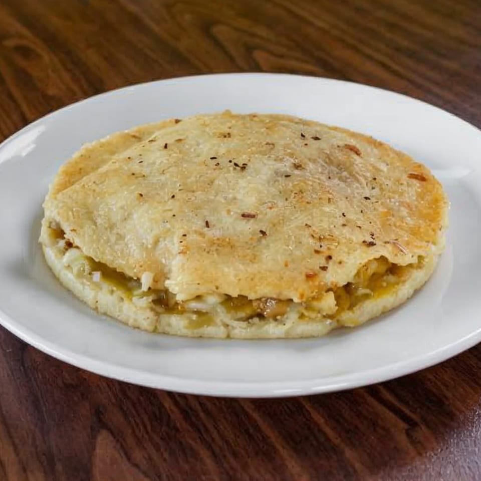 A golden-brown La Perla Tapatia Goshen quesadilla, filled with cheese and onions, on a white plate.