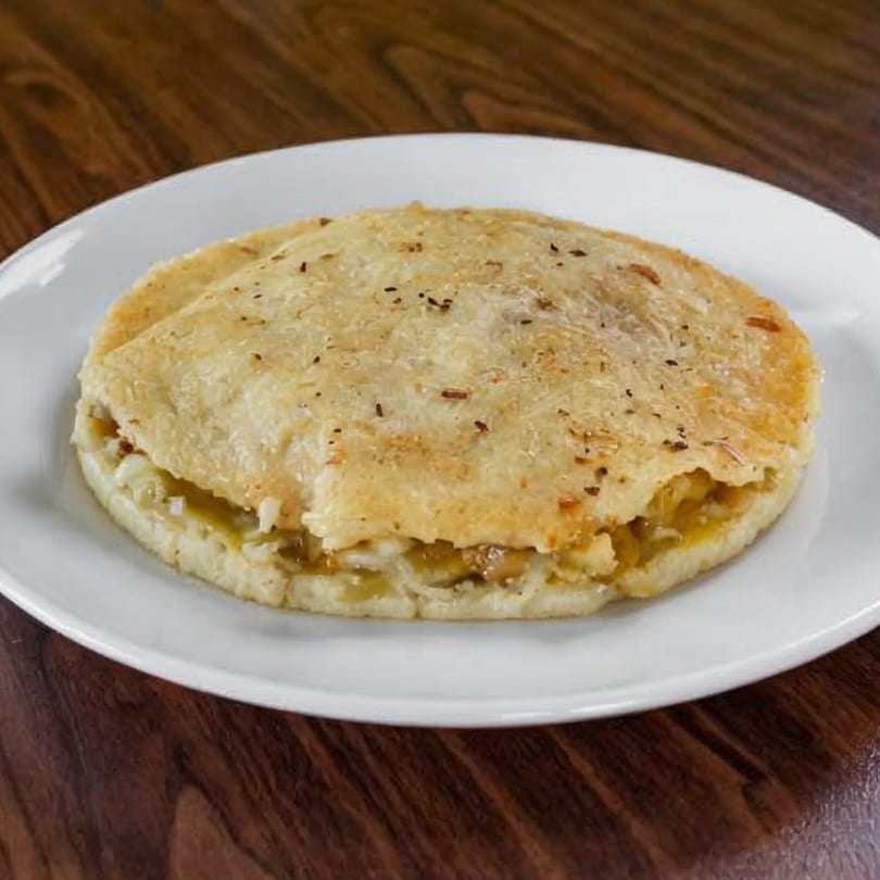 A golden-brown La Perla Tapatia Goshen quesadilla, filled with cheese and onions, on a white plate.