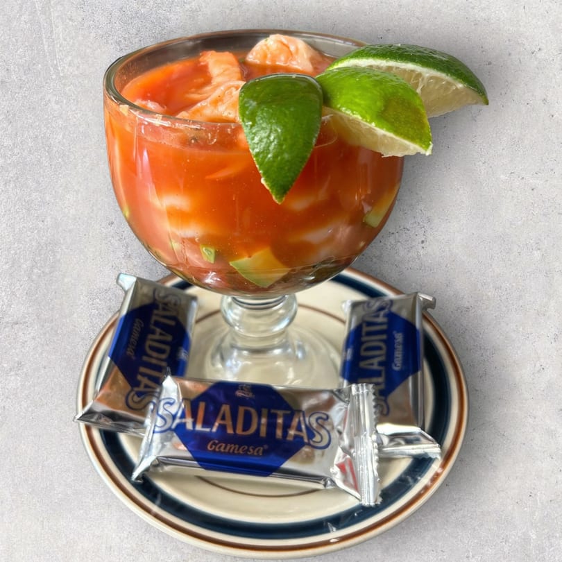 Mexican shrimp cocktail with avocado and lime, served with Saliditas crackers on a plate.